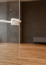 Glass door with metallic handle open in to the empty room with black wall and wooden floor. Royalty Free Stock Photo