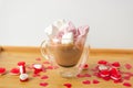 Glass double bottom cup of coffee with marshmallow in heart form. On the wooden table with red paper hearts and candies. Royalty Free Stock Photo