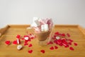 Glass double bottom cup of coffee with marshmallow in heart form. On the wooden table with red paper hearts and candies. Royalty Free Stock Photo