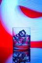 A glass with a drink and ice cubes on a red background Royalty Free Stock Photo