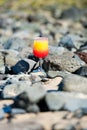 A glass with drink on the stone beach by the sea