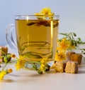 Glass of drink, tea, sugar cubes, yellow daisies on the table, still life