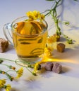 Glass of drink, tea, sugar cubes, yellow daisies on the table, still life