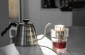 Glass with drip coffee bag and kettle on light grey table Royalty Free Stock Photo