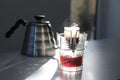 Glass with drip coffee bag and kettle on light grey table Royalty Free Stock Photo