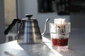 Glass with drip coffee bag and kettle on light grey table Royalty Free Stock Photo