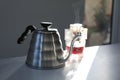 Glass with drip coffee bag and kettle on light grey table Royalty Free Stock Photo