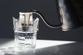 Glass with drip coffee bag and metal kettle on light grey table, closeup Royalty Free Stock Photo