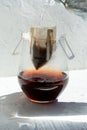 Glass with drip coffee bag with water drop and jet from the teapot on white background. Instant fresh morning drink