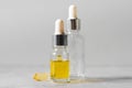 Glass dropper bottle with essential oil and omega capsule on grey background. Homeopathy concept