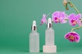 Glass dropper bottles with a pipette with a white rubber tip on a green background. Cosmetic bottle on a pedestal