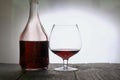 A glass of dry red wine. Bottle of wine. Stand on wooden boards. Shot in backlight Royalty Free Stock Photo