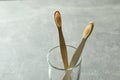 Glass with eco friendly toothbrushes on gray background