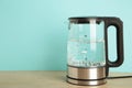 Glass electric kettle with boiling water on blue background Royalty Free Stock Photo