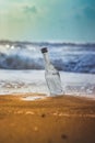 Glass empty bottle in coast sand and sky with clouds. Bottle in the beach sand with Text copy space. Empty bottle trash on sand Royalty Free Stock Photo