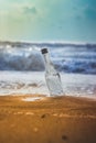 Glass empty bottle in coast sand and sky with clouds. Bottle in the beach sand with Text copy space. Empty bottle trash on sand Royalty Free Stock Photo