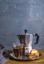 Glass espresso coffee on rustic wooden board, cantucci biscuits and steel Italian Moka pot, grey background