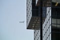 Glass facade detail of modern building and airplane on the sky in the background Royalty Free Stock Photo