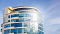 Glass facade of modern multi-storey building with sun glare in windows against blue sky background_ Royalty Free Stock Photo