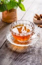 Glass figured cup of healing infusion of birch mushroom chaga with chaga pieces and leaves on wooden table