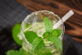 A glass filled with alcohol beverage from juicy lime, rum, fresh mint and crushed ice on a dark wooden background. Summer mojito w Royalty Free Stock Photo