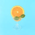 A glass filled with orange juice and decorated with a slice of orange and green leaves on a blue background. Summer refreshing Royalty Free Stock Photo