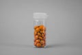 Glass flask with orange pills on a gray background