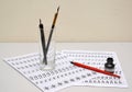 Glass with fountain pens and black ink lie on sheets of calligraphical copy-books Royalty Free Stock Photo