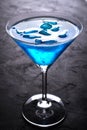 Glass of fresh cold blue cocktail with ice cubes on dark bar table Royalty Free Stock Photo