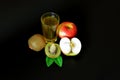 A glass of fresh fruit juice on a black background, next to a ripe red apple and pieces of kiwi fruit Royalty Free Stock Photo