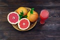 A glass of fresh grapefruit juice and grapefruit fruits on a wooden table. Healthy food Royalty Free Stock Photo