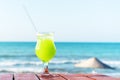 A glass of fresh green tropical fruit juice on the beach, on the table, against the sea Royalty Free Stock Photo