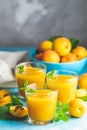 Glass of fresh healthy apricot or peach smoothie or juice on light blue concrete surface table. Sunny light. Shallow depth of the Royalty Free Stock Photo