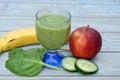 Glass of fresh healthy green smoothie, a red apple, banana, cucumber, and spinach Royalty Free Stock Photo