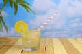 A glass of fresh lemonade on ice with a lemon garnish and a fun red and white barber pole style straw on a rustic wooden table Royalty Free Stock Photo