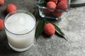 Glass with fresh lychee juice on grey table