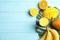 Glass of fresh mango drink and tropical fruits on color wooden background, top view Royalty Free Stock Photo