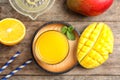 Glass of fresh mango drink and tropical fruits on wooden table Royalty Free Stock Photo
