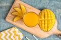 Glass of fresh mango juice and cut fruits on wooden table Royalty Free Stock Photo