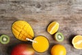 Glass with fresh mango juice and tasty fruits on wooden table, flat lay Royalty Free Stock Photo