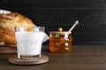 Glass with fresh milk, honey and bread on wooden table. Space for text Royalty Free Stock Photo