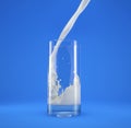 Glass of fresh milk with pouring and splash. On blue Royalty Free Stock Photo