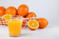 A glass of fresh orange juice and a basket with fresh oranges