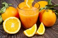 A glass of fresh orange juice and oranges on wooden background Royalty Free Stock Photo