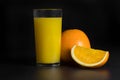 A glass of fresh orange juice and slices of orange on a black background, close-up Royalty Free Stock Photo