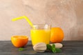 Glass with fresh orange juice and tubule, oranges, mint and wooden juicer on wooden table against color background Royalty Free Stock Photo