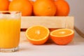 A glass of fresh orange juice and a wooden box with oranges