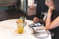 Glass of fresh passion fruit drink on table with woman using mobile phone. Royalty Free Stock Photo