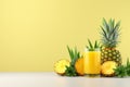 Glass of fresh pineapple juice and ripe pineapples on vibrant yellow background with copy space Royalty Free Stock Photo
