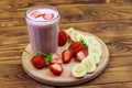 Glass of fresh smoothie of strawberry and banana on wooden table